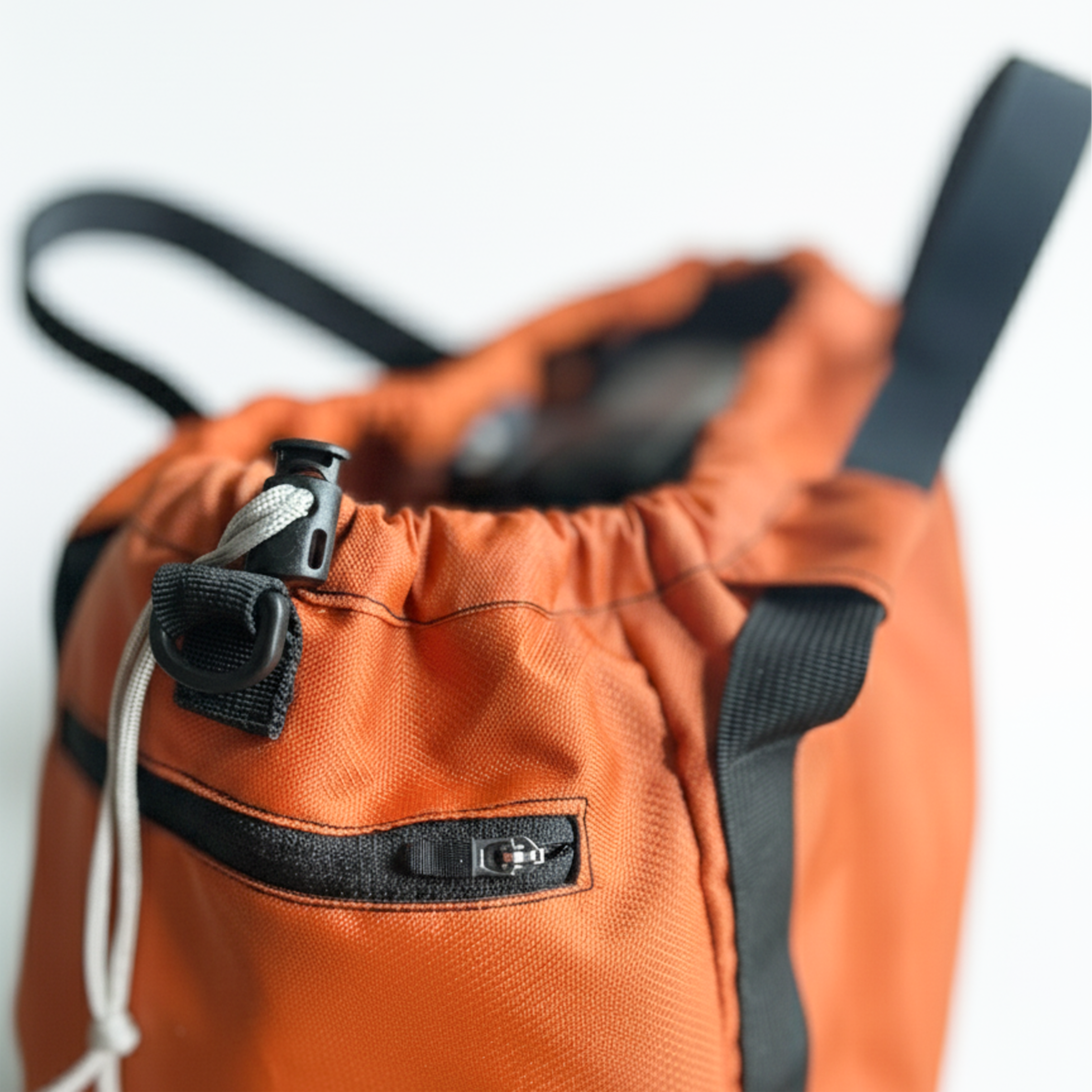 Detail shot of an orange nylon gym tote, highlighting the side zippered pocket.