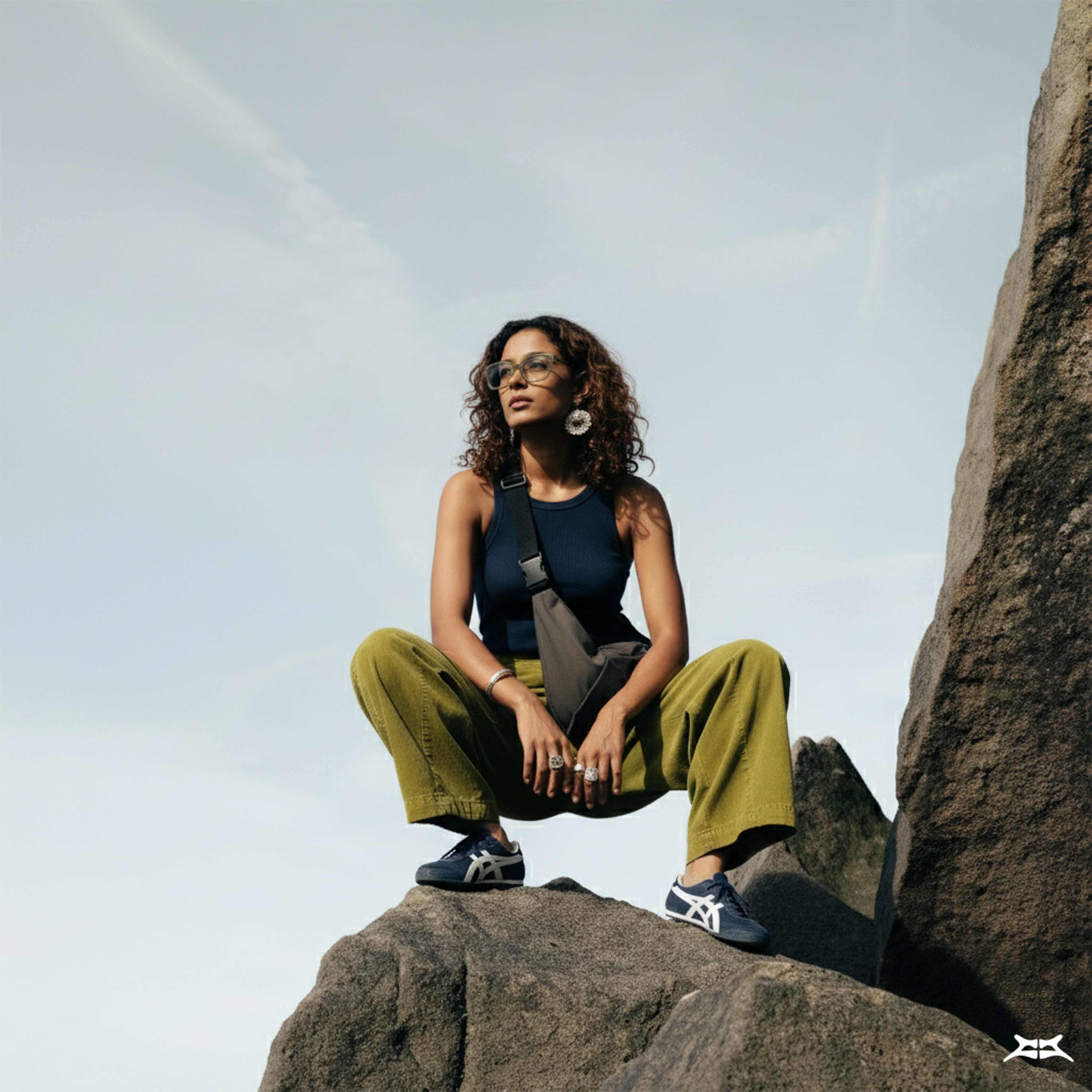 Woman in outdoor fashion, wearing a grey water-resistant crossbody crescent bag.