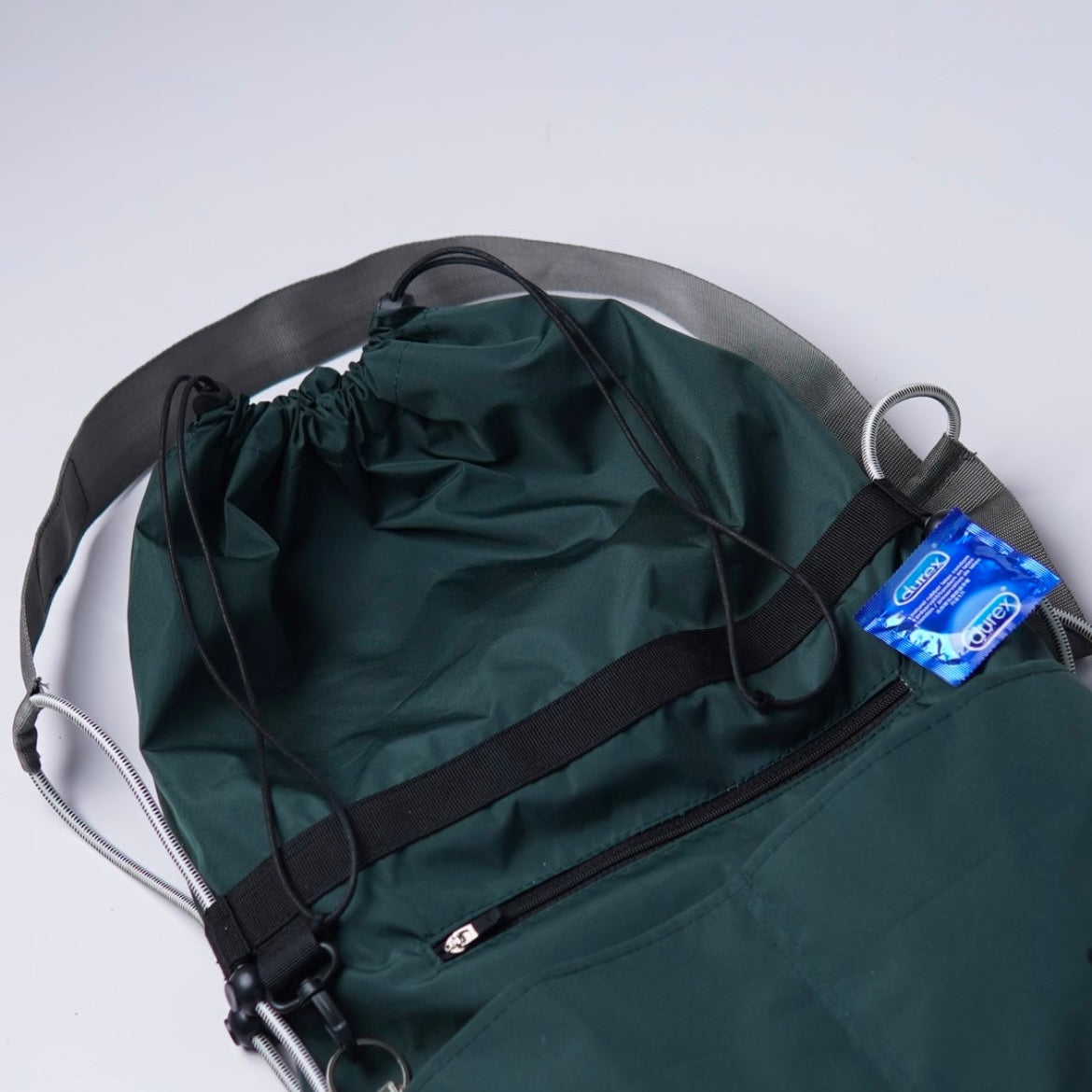 Green drawstring bag with black straps on a white background