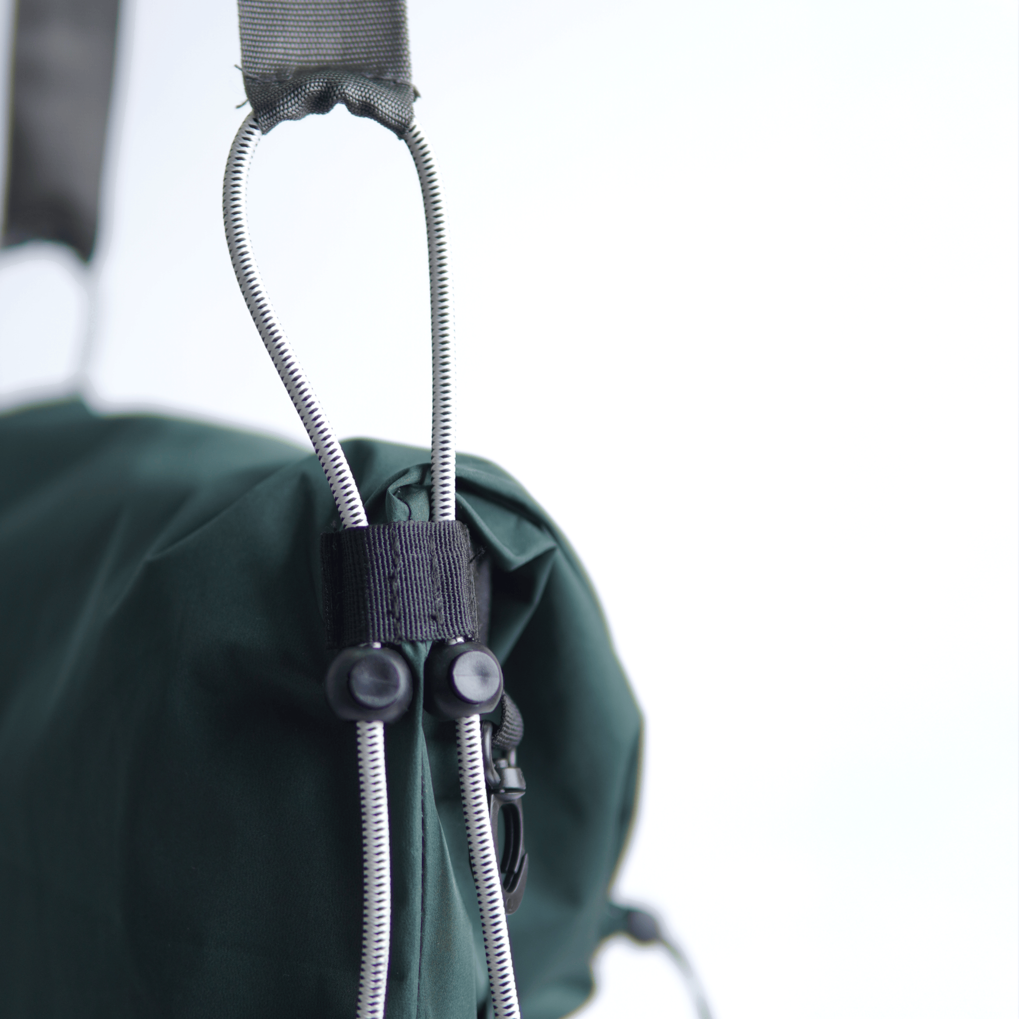 Close-up detail of a forest green water-resistant bag's strap and cord lock.