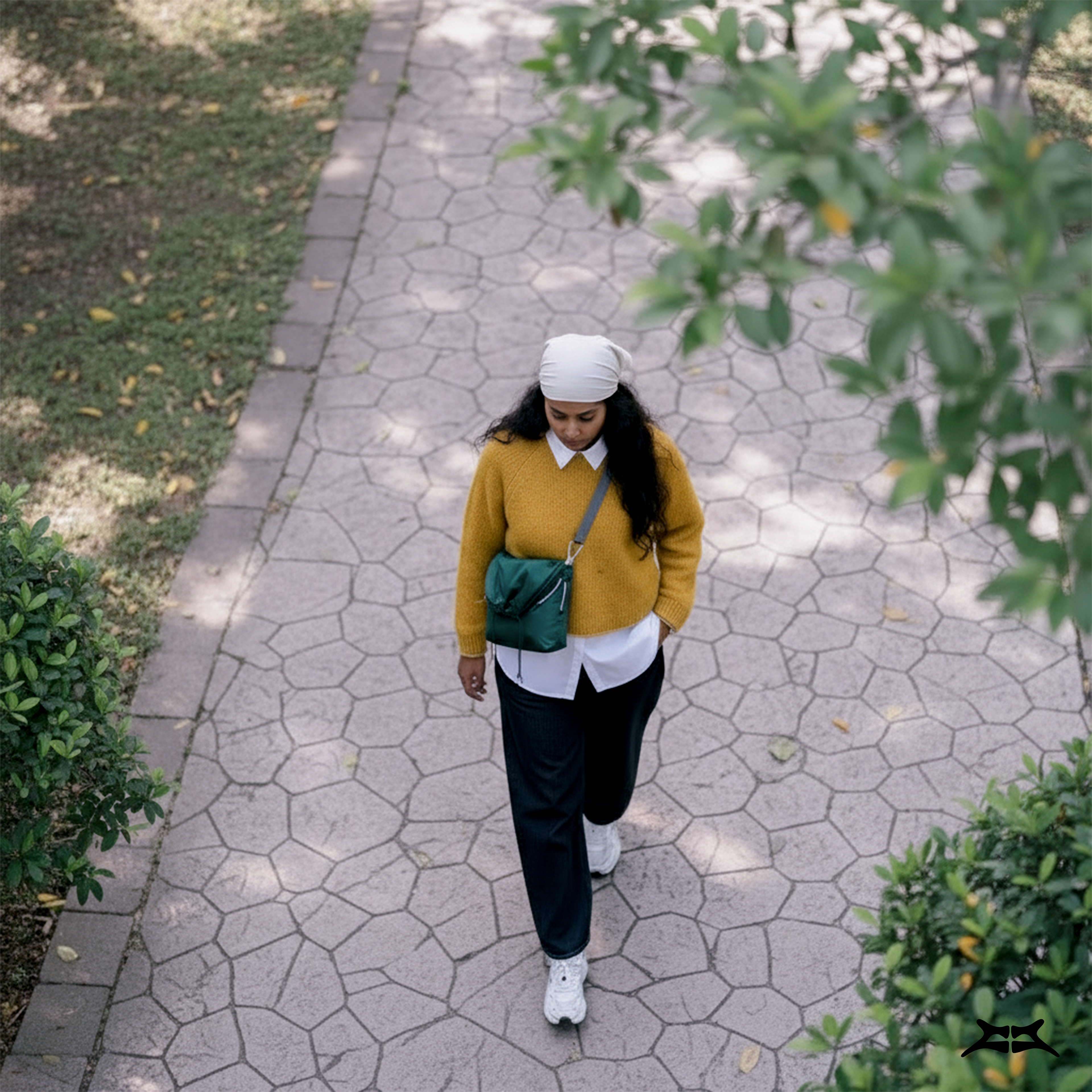 Overhead view of a woman walking with a dark green crossbody utility bag.