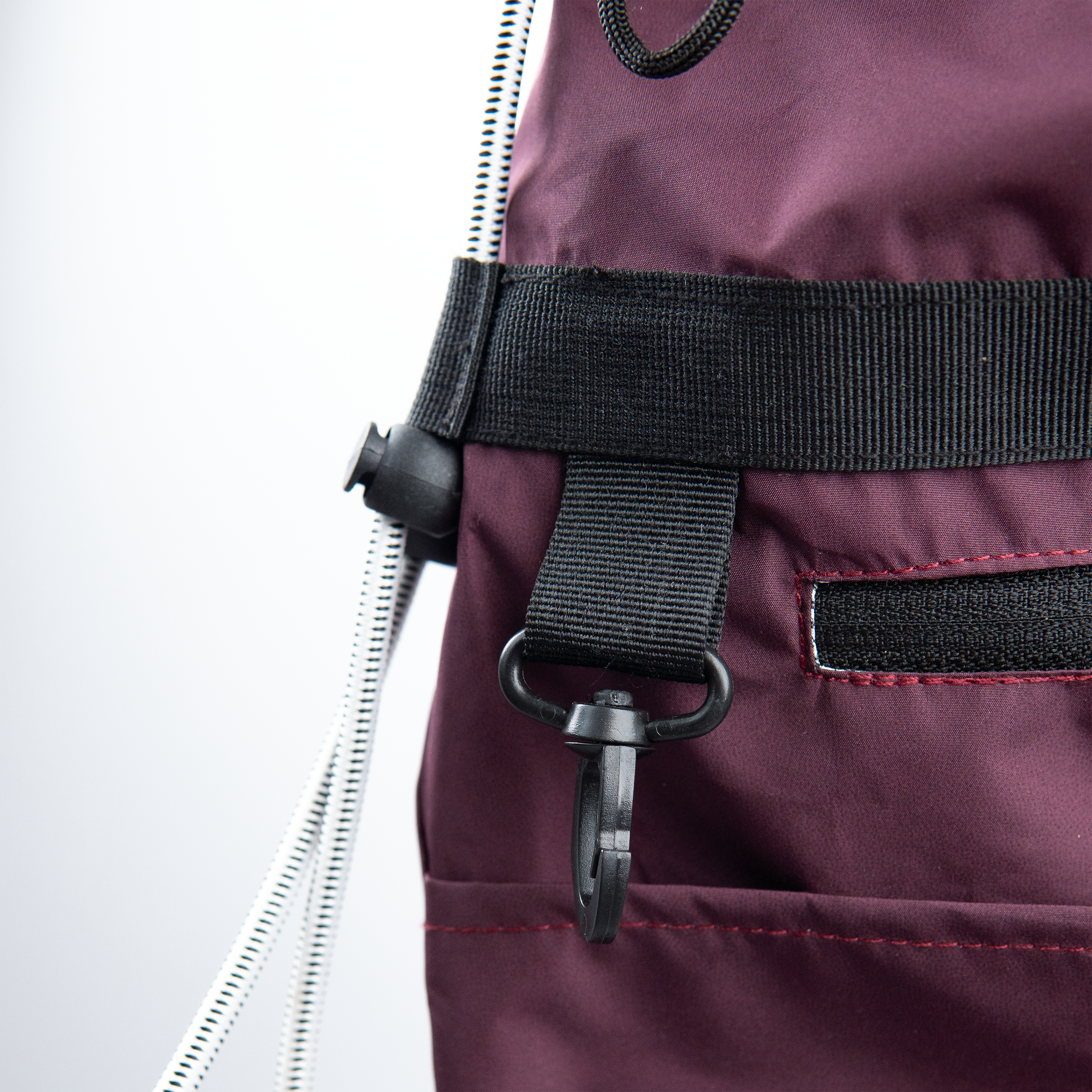 Close-up texture of a water-resistant nylon sling bag in a wine-red maroon color.