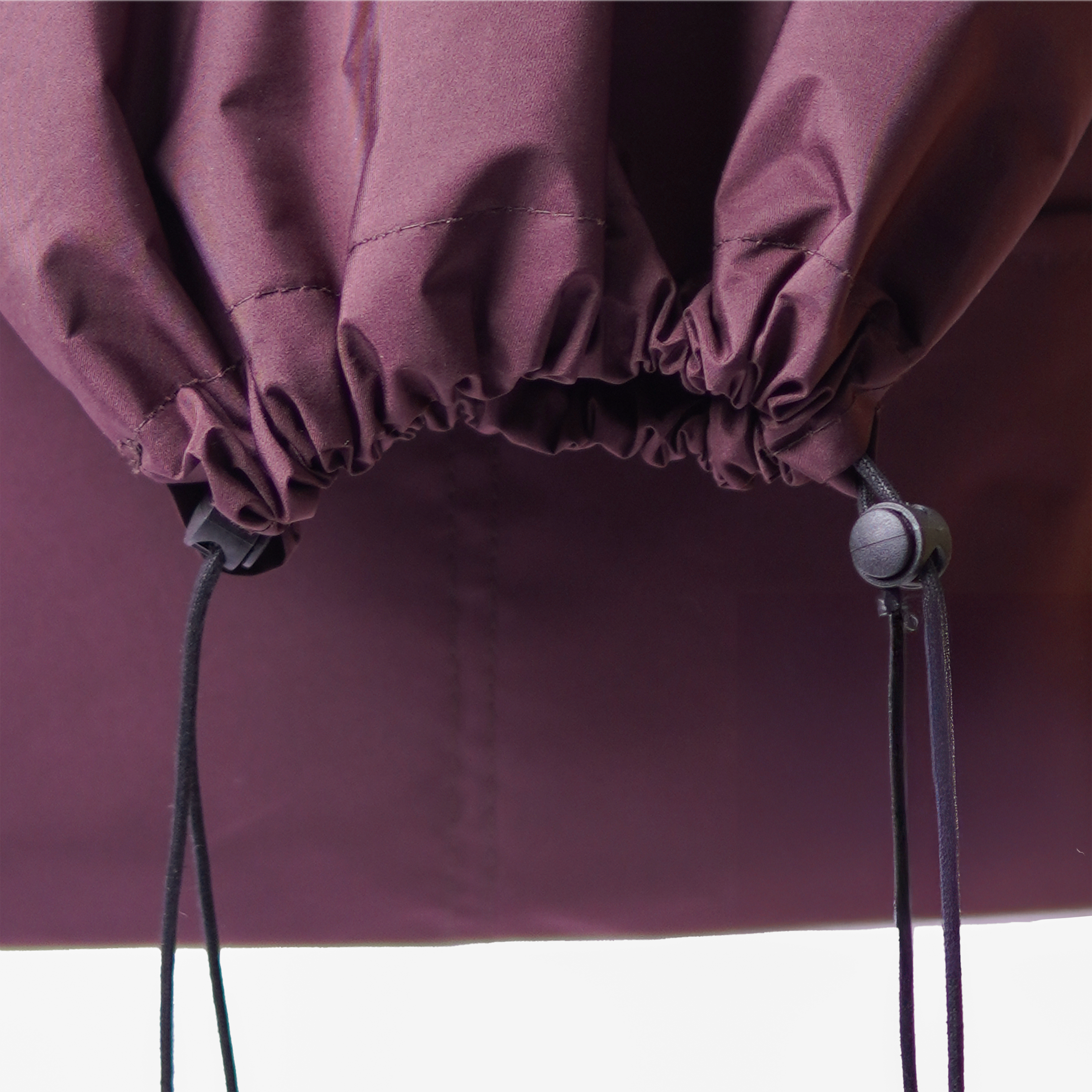 Detailed view of a water-resistant crossbody bag, showing the maroon nylon fabric and black cord.